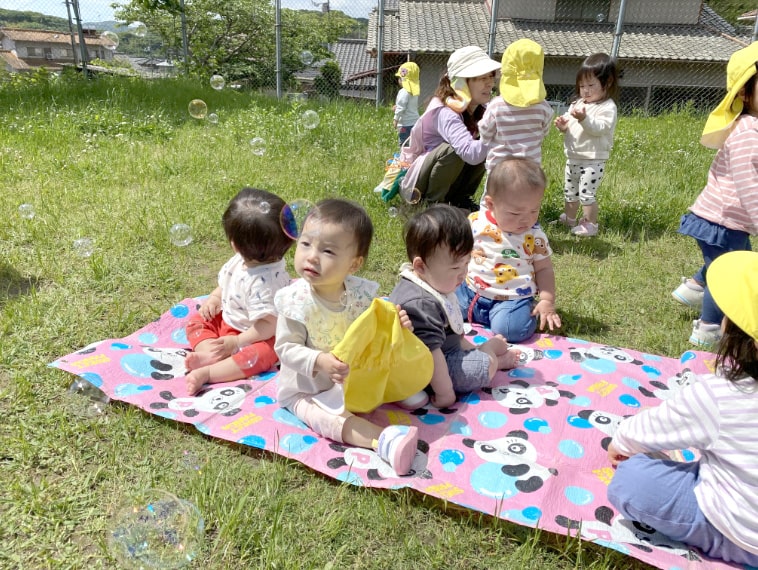 ピクニックシートに座る園児の写真