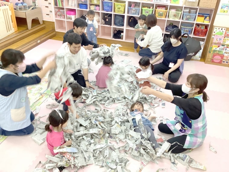 新聞紙で遊ぶ子どもの写真