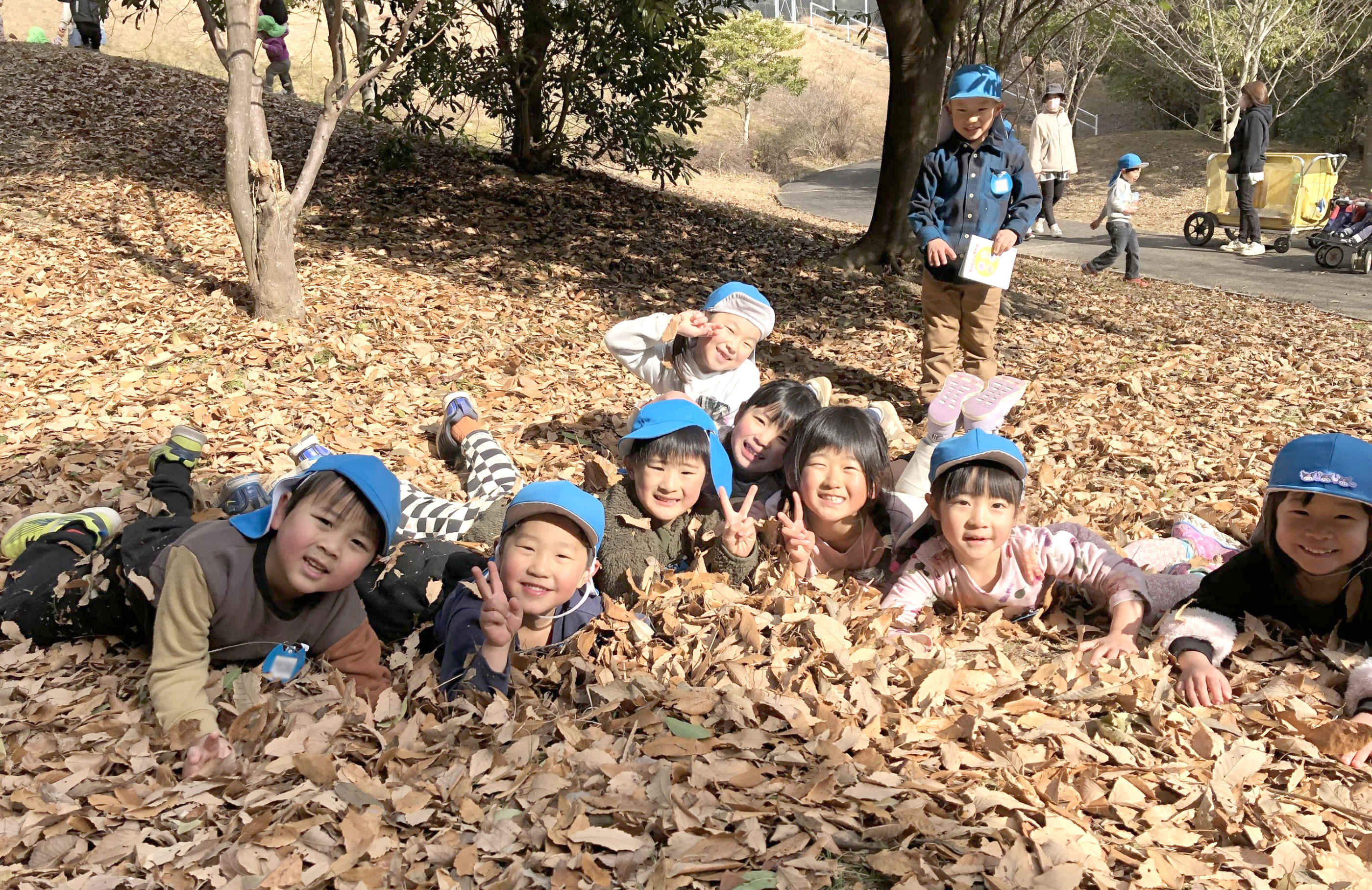落ち葉の上で寝転ぶ子どもたち