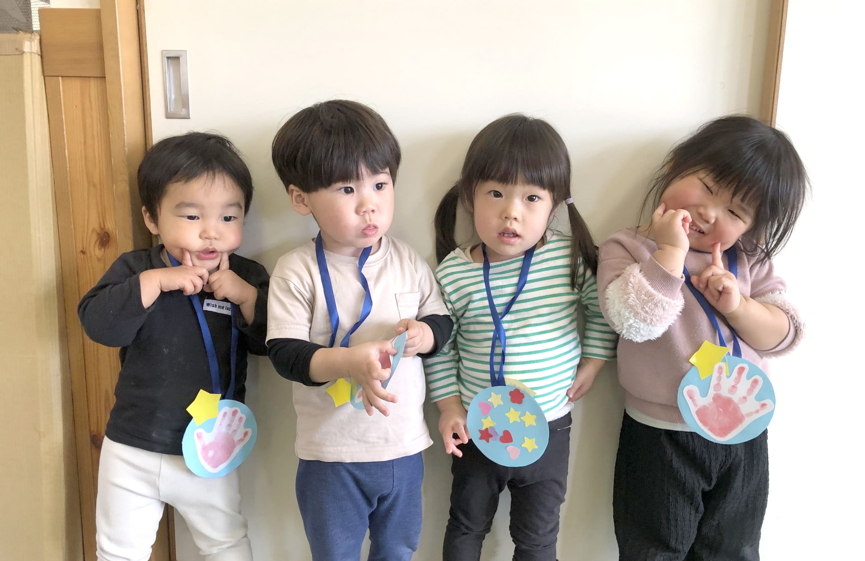 紙のメダルをかけてもらってる子どもたち