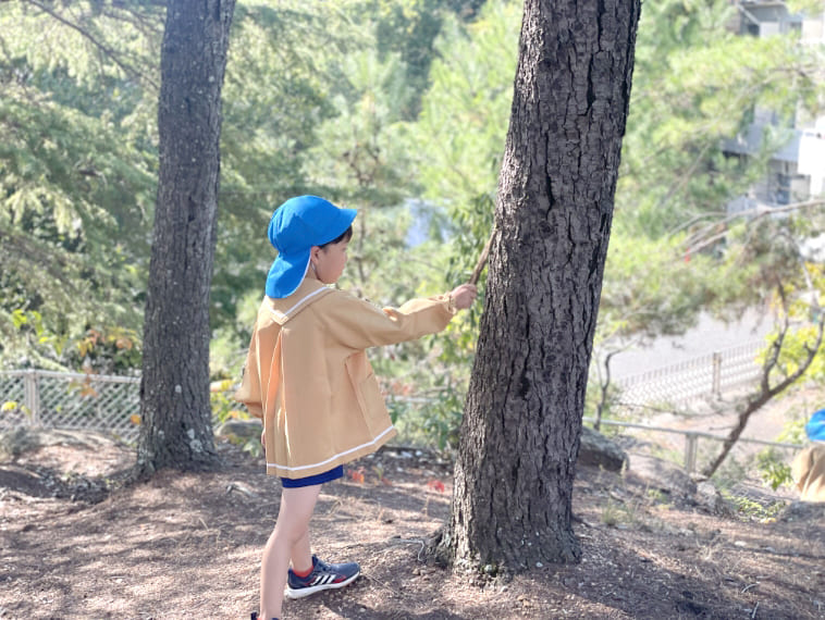木の前にいる園児の写真