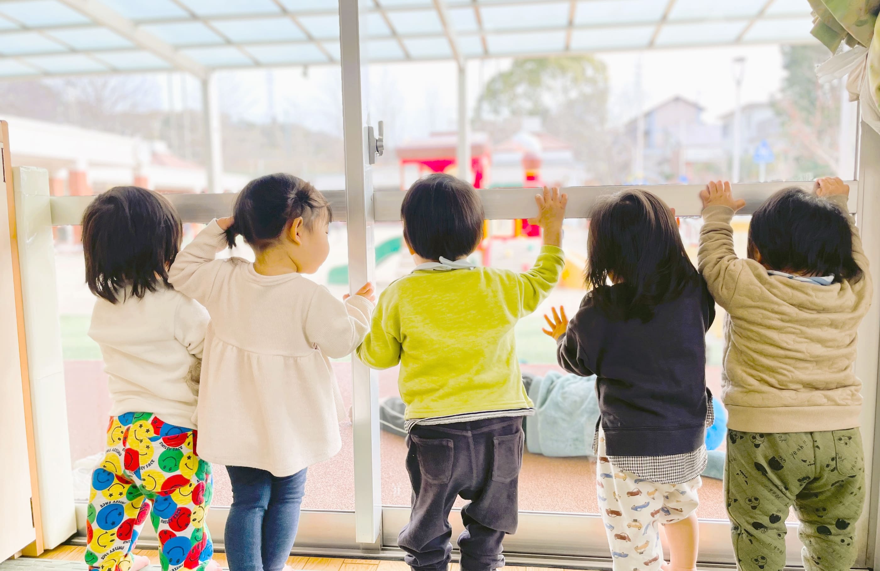 屋内から窓の外を見る子どもたち