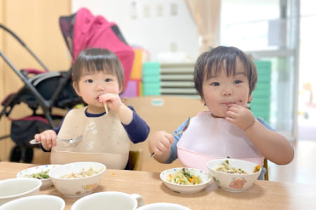 給食を食べる乳児の写真