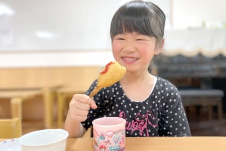 アメリカンドッグを食べている子どもの写真